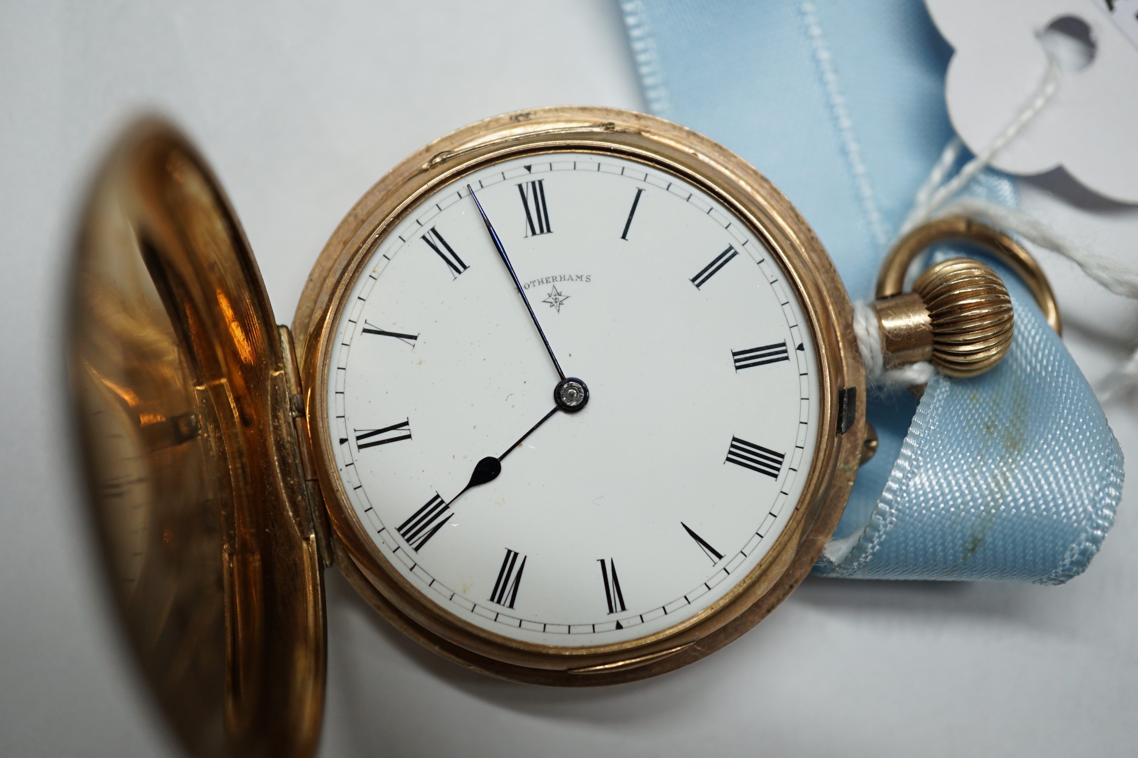 An early 20th century engraved 9ct gold hunter fob watch, with Roman dial, gross 36.7 grams, on a blue sash with yellow metal mounted hardstone fob.